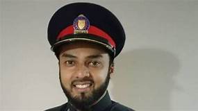 Aisian man 35 years old a clean short black beard. wearing the Toronto Police cap. The cap is Black with a red horizontal stipe.