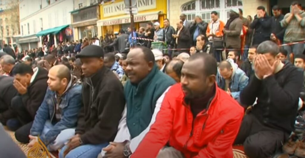 Men with black skin on their knees completely fill the street. They are literally shoulder to should