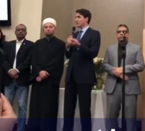 Justin Trudeau wears a blue suit Standing beside him a Imam  wioth a white turban