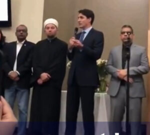 Justin Trudeau wears a blue suit Standing beside him a Imam wioth a white turban