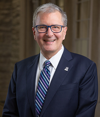 President Western University. 55 years old. Grey hair. Blue suit white shirt and blue white striped neck tie